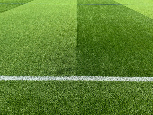 Close-up of a vibrant green football field with a white line marking, highlighting sports venue texture.