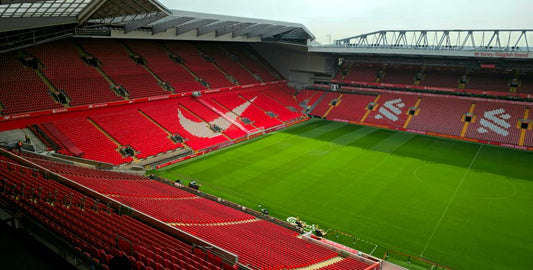 Aerial view of Anfield Stadium, Liverpool, showcasing its empty red seats and green pitch.