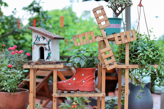 Garden scene with decorative birdhouse, windmill, and assorted potted plants.